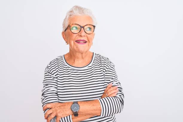 senior grey-haired woman wearing striped navy t-shirt glasses over isolated white background smiling looking to the side and staring away thinking. - mannered imagens e fotografias de stock