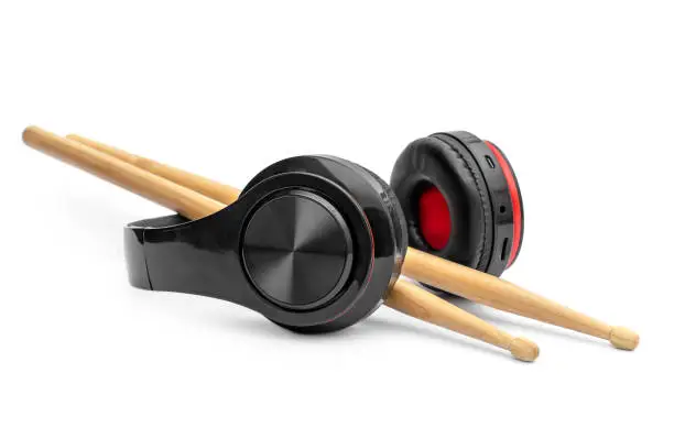 Headphones with drumsticks on white.