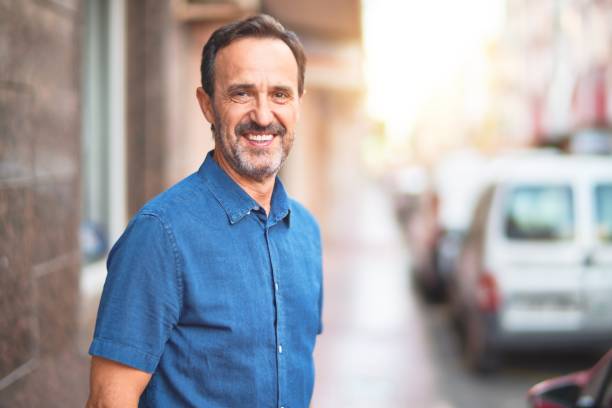 istock Middle age handsome man standing on the street smiling 1185950040