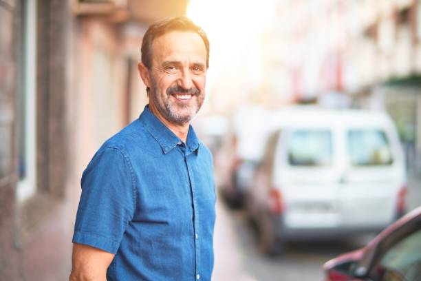 istock Middle age handsome man standing on the street smiling 1185950098