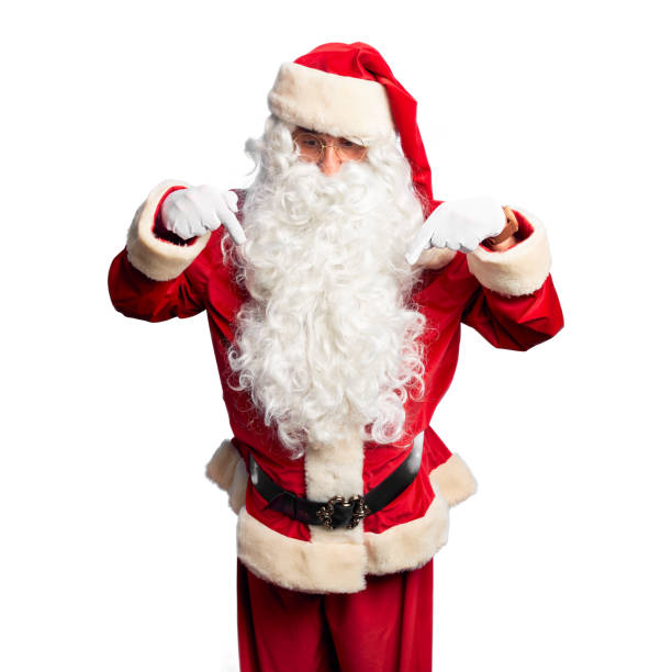 istock Middle age handsome man wearing Santa Claus costume and beard standing Pointing down with fingers showing advertisement, surprised face and open mouth 1185950134