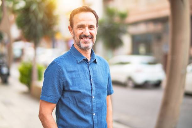 istock Middle age handsome man standing on the street smiling 1185950174