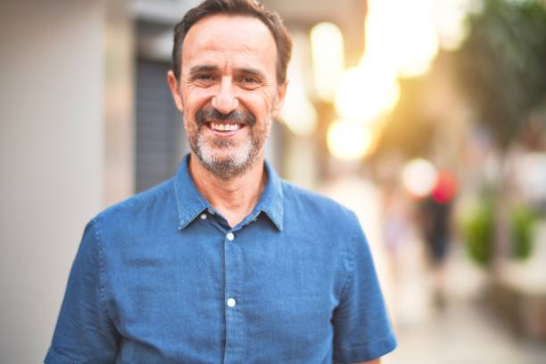 istock Middle age handsome man standing on the street smiling 1185950195
