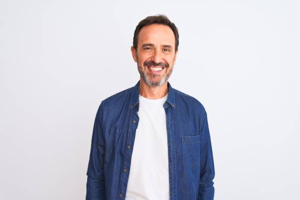 hombre guapo de la mediana edad con camisa de mezclilla azul de pie sobre fondo blanco aislado con una sonrisa feliz y fresca en la cara. una persona afortunada. - spanish and portuguese ethnicity fotos fotografías e imágenes de stock