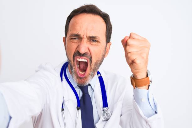 middle age doctor man wearing stethoscope make selfie over isolated white background annoyed and frustrated shouting with anger, crazy and yelling with raised hand, anger concept - bizarre making a face men one person imagens e fotografias de stock