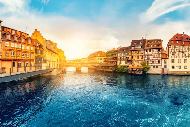 Photo of Colorful sunset in the region of Little France in the city of Strasbourg. Famous half-timbered houses, the river Ill and the bridge of St. Martin. Popular tourist destinations in Europe