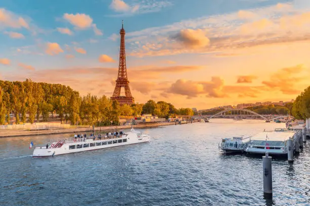 Photo of The main attraction of Paris and all of Europe is the Eiffel tower in the rays of the setting sun on the bank of Seine river with cruise tourist ships