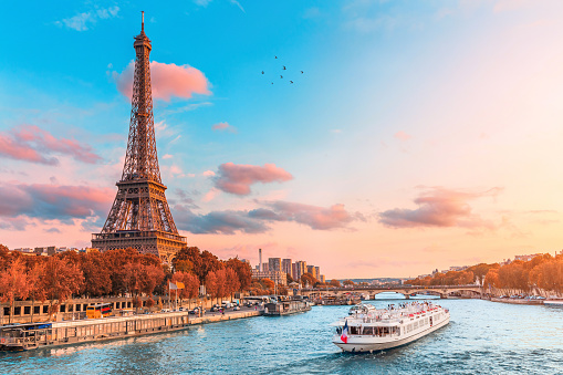 La principal atracción de París y toda Europa es la torre Eiffel en los rayos de la puesta de sol en la orilla del río Sena con cruceros turísticos photo