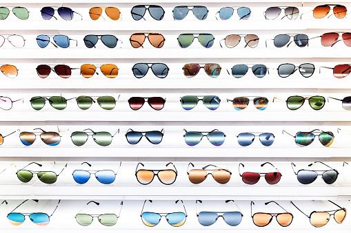 shelves with large number of colorful and fashionable sunglasses on a shop display
