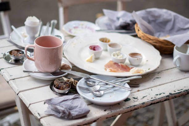 Stylish white breakfast table with dirty dishes after the meal.