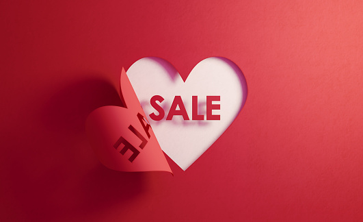 Sale text inside of a red folding heart shape on white background. Horizontal composition with  copy space. Sale concept.