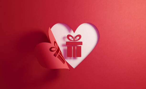 Gift box icon inside of a red folding heart shape on white background. Horizontal composition with copy space. Gift concept.