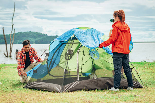 istock friends setting up the tent outdoor by the lake during camping 1185968942