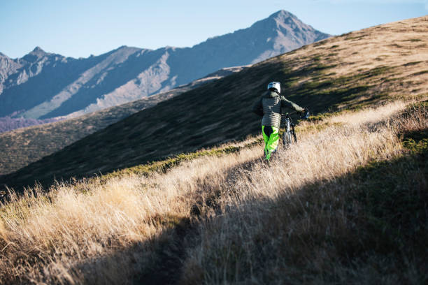 Rear view of mountain biker pushing his bicycle in mountain.