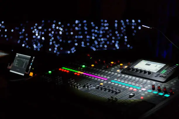 Audio sound mixer console with buttons and sliders with lights at the concert. Selective focus.