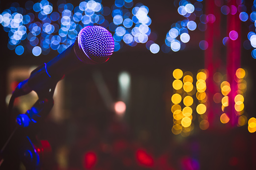 Close up of microphone in concert hall or conference room. Microphone on stage with colorful blurred lights