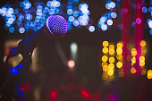 Close up of microphone in concert hall or conference room. Microphone on stage with colorful blurred lights.