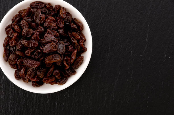 istock Raisins in small dish on black stone background 1185982807
