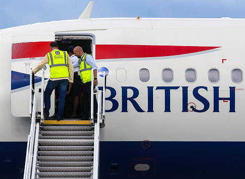 Bucharest, Romania - July 15, 2019: Ramp agents secures the ladder of British Airways G-EUXG aircraft parked in the VIP reception area of \