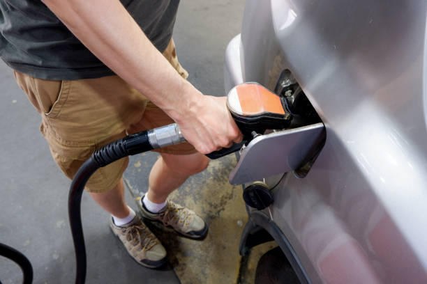 un uomo che tiene la pompa che riempie la benzina. pompando benzina nel serbatoio. un'auto fa rifornimento sulla stazione di servizio - pompa daria foto e immagini stock