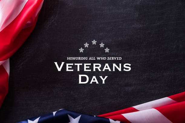 istock Happy Veterans Day. American flags veterans against a blackboard background. 1186002076