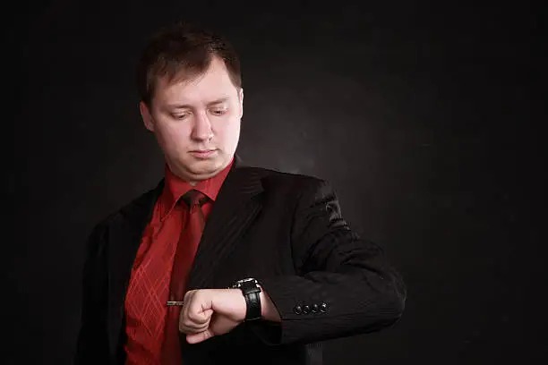 business man in suit and red shirt looking at the watch