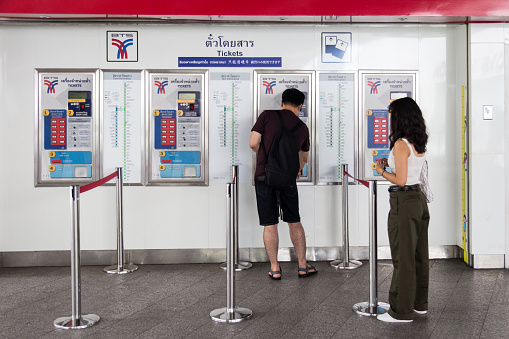 Bangkok, Thailand - 8th August 2017: Man and woman getting tickets from the ticket machine at BTS Skytrain station Asoke. The Skytrain has been running since 1999.