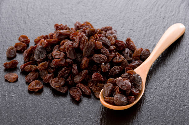 istock Raisins in wooden spoon on black stone background 1186022612