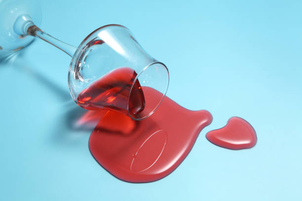 istock Red wine spilled from glass over blue background with a blank space for a text,  Red wine spilled on color table 1186023895