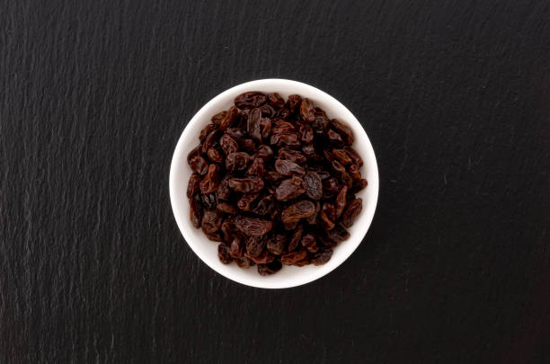 Raisins in small dish on black stone background
