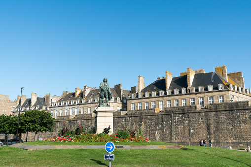 Saint-Malo, Ille-et-Vilaine / France - 19 August 2019: statue of Betrand-Francois Mahe de la Bourdonnais with Saint-Malo city walls behind
