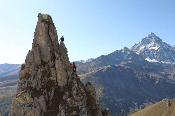istock Mountaineer ascends to pinnacle summit, teammate 1186032088