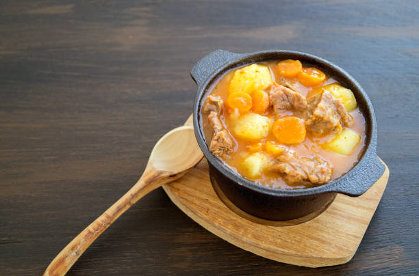 Caldo de Costilla, a soup like dish of beef ribs and potato served in a porcelain soup plate. It has been served on a rustic table and is ready to eat. Horizontal format. No people.