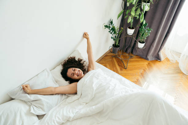 istock young pretty woman in bed with white sheets bright light copy space 1186036416