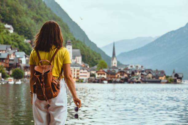 женщина, стоящая на пляже, глядя на hallstatt город копию пространства - town of progress стоковые фото и изображения