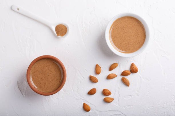 istock Apricot kernel butter smooth, urbech. Natural paste from apricot kernels in white bowls on white table. Top view. 1186038788