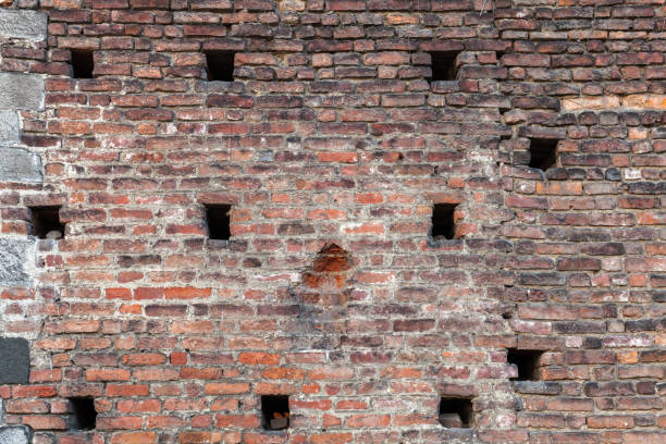 Old grungy brick wall with small holes, frontal view, background photo texture