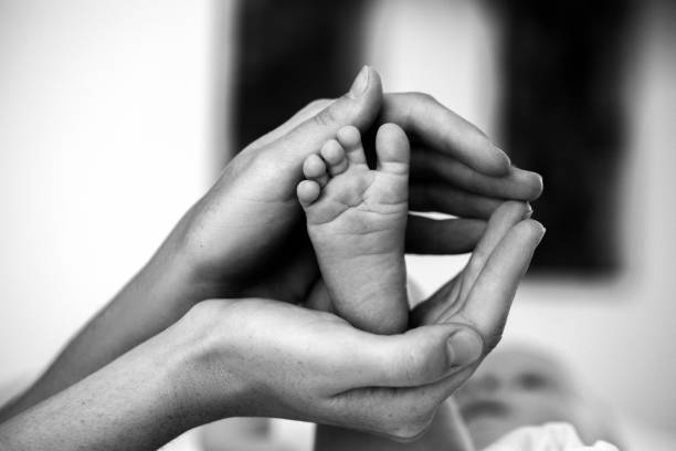 赤ちゃんの足を母の手 - human foot baby black and white newborn ストックフォトと画像