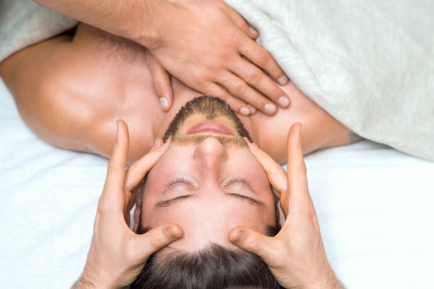 istock Handsome young man receiving a head massage from a two masseurs. 1186044764