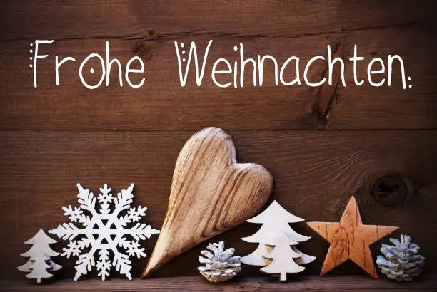 German Calligraphy Frohe Weihnachten Means Merry Christmas. Wooden Christmas Decoration Like Tree, Heart, Fir Cone. Brown Wooden Background