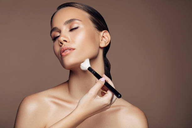 istock Beautiful young woman applying foundation powder 1186047579