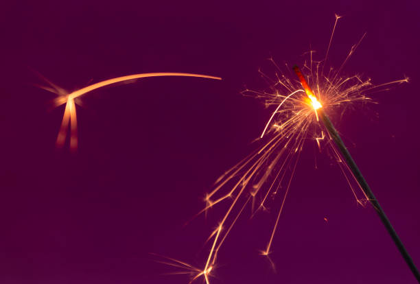 istock Burning christmas sparkler on purple background 1186048568