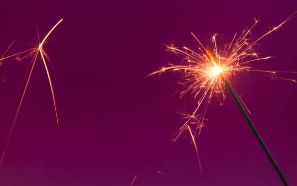 istock Burning christmas sparkler on purple background 1186048581