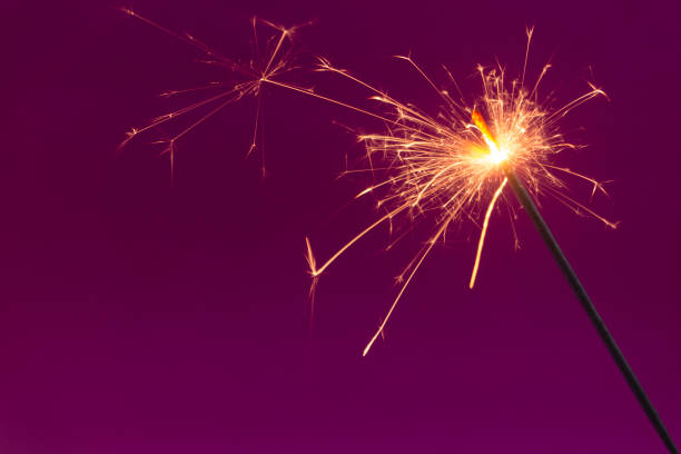 istock Burning christmas sparkler on purple background 1186048604