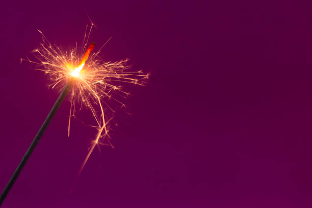 istock Burning christmas sparkler on purple background 1186048666