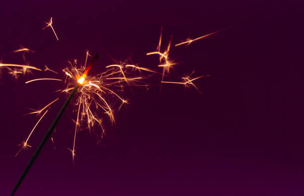 istock Burning christmas sparkler on purple background 1186048798