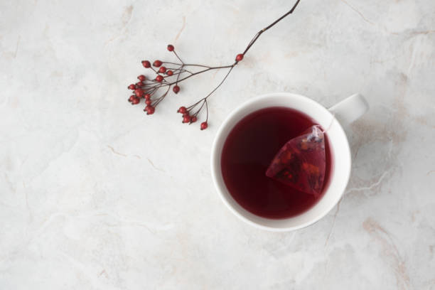 istock Fruity tea in tea pyramid bag in white cup and red berries on marble background. Cozy winter mood, top view 1186050743