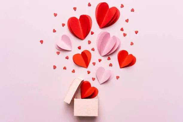 Photo of Valentine day composition with gift box and red hearts, photo template on pink background.