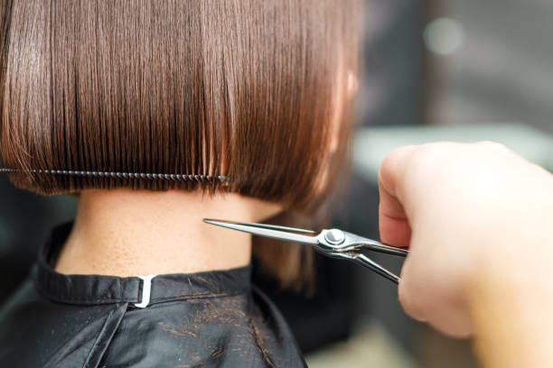 les mains du coiffeur coupent les cheveux courts bruns. - hairstyle photos et images de collection