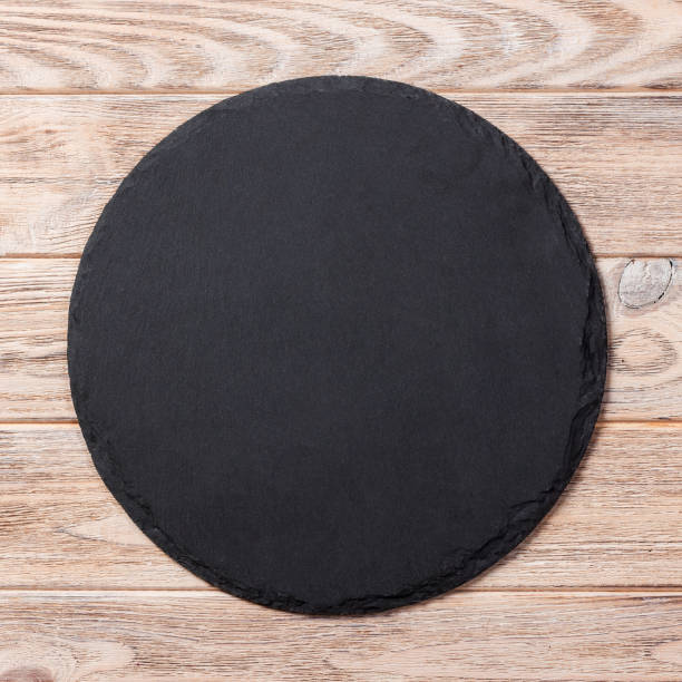 istock Round plate on table. black dish on wooden background. copy space 1186057361